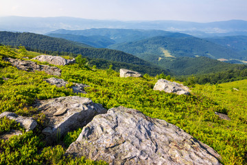 mountain landscape. valley with stones on the hillside. forest on the mountain under the beam of light falls on a clearing at the top of the hill.