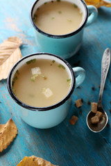 Two mugs of soup on blue wooden background