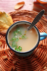 Mug of soup on wicker mat