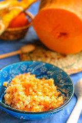 Pumpkin porridge with rice in a blue vintage plate and with pumpkin rustic background.