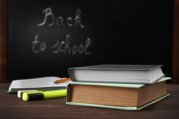 School equipment on desk on blackboard background