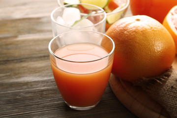 Citrus juice with ice and fresh fruits on cutting board