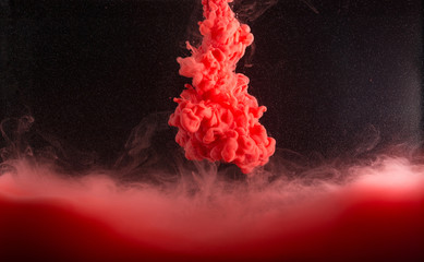 Red ink in water on dark.