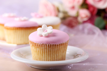 Tasty cupcake on saucer, on light background