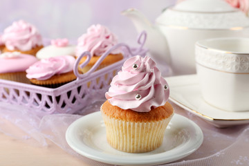 Tasty cupcake on saucer, on light background