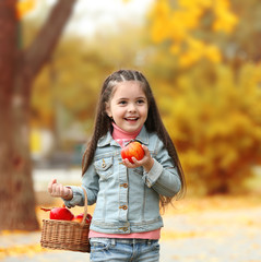 Beautiful little girl holding basket of apples, outdoor