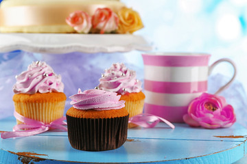 Cake with sugar paste flowers and cupcakes, on light background