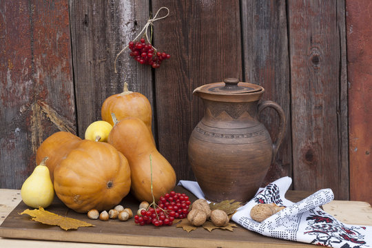 Autumn still life with pumpkins and autumn berry and vegetables on old wooden background, closeup