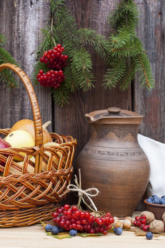 Autumn still life with pumpkins in basket and autumn berry on old wooden background, closeup