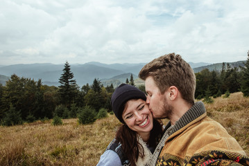 stylish beautiful traveling tender couple kissing in the mountai