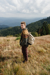 Naklejka na ściany i meble stylish beautiful traveling man hiking in the mountains on a bac