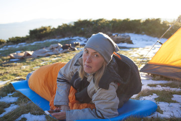 The girl with the phone lying in a sleeping bag.