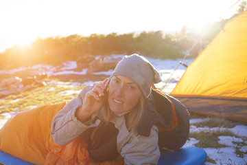 The girl with the phone lying in a sleeping bag.
