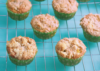 Apple crumb spiced muffins on a grill grate on green pastel wooden table