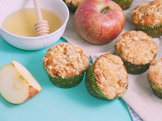 Apple crumb spiced muffins on on green pastel wooden table with table napkins and an apple