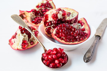 Pomegranates seeds on the spoon and pomegranates pieces.