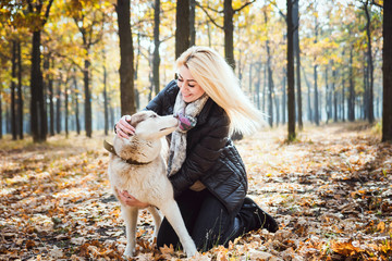 young beautiful female having fun with siberian husky in autumn park