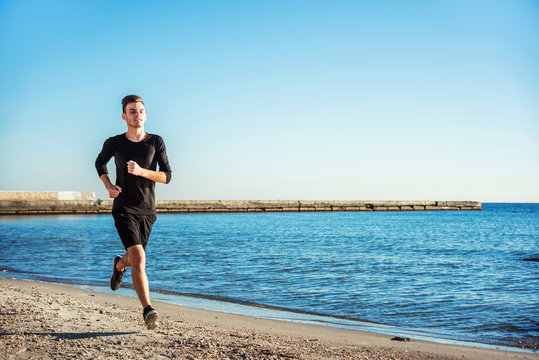 Running Man. Male Runner Jogging During The Sunrise On Beach