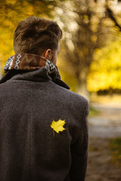 beautiful happy stylish man in a coat with little yellow leaf on