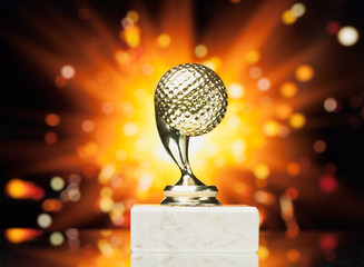 golf ball trophy against shiny sparks background