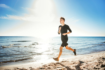 Running man. Male runner jogging during the sunrise on beach