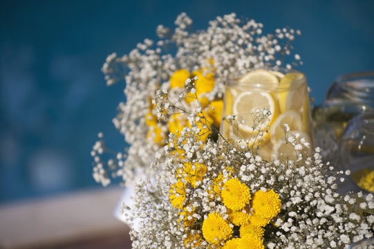 Wedding decoration with gypsophila and lemon in glass vase on the table near the outdoor pool, artistic soft focus 