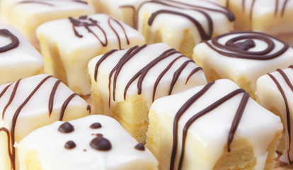 Assorted squares of lemon cake covered in icing and decorated with chocolate.