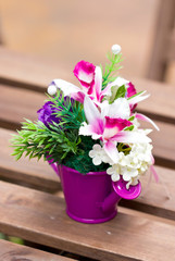 Artificial flowers in colorful metallic vase.