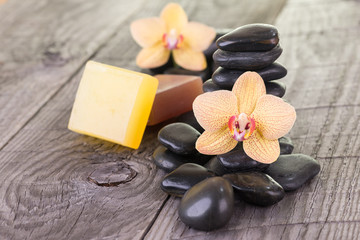 Fototapeta na wymiar Yellow Phalaenopsis orchid, black stones and soaps on wooden background 