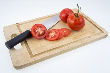 Ripe tomatoes and knife on cutting board on white background