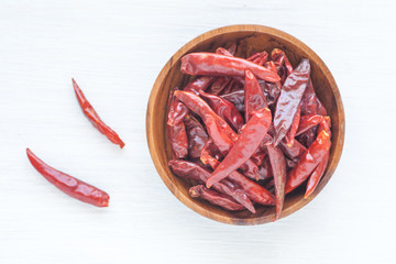 Dried chili pepper in wooden bowl on white background