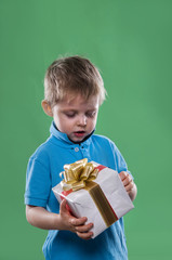 a little boy holding a gift box in his hands on the green background
