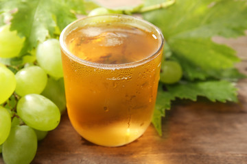 Glass of cool grape juice on wooden table, closeup