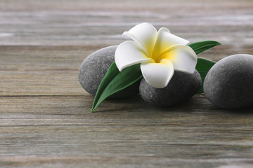 Spa stones with flower on wooden background