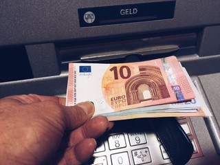 Mann nimmt Geldscheine aus Bank Automat