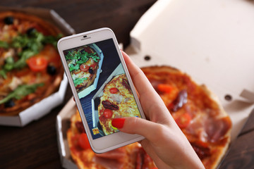 Woman taking a photo of pizza with the smartphone © Africa Studio
