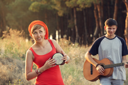 Two happy friends with musical instruments in the forest outdoors