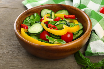Vegetable salad with cucumbers  on wooden background decorated with green checked cotton serviette and sweet pepper