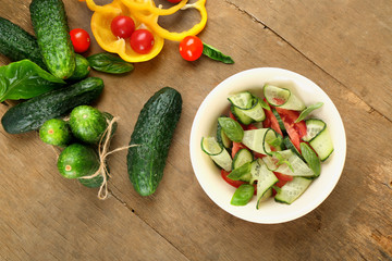 Vegetable salad with cucumbers on wooden background