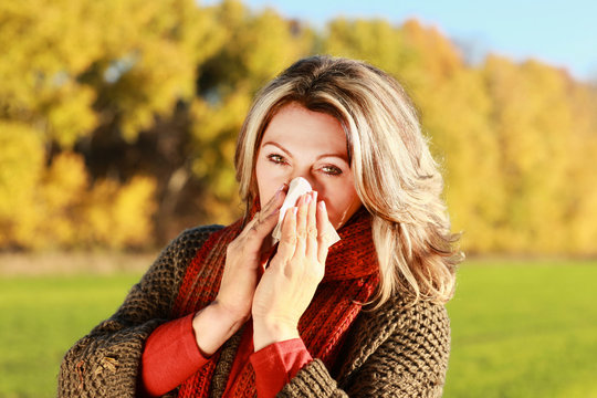 Frau mittleren Alters mit Taschentuch und Erkältung im Herbst