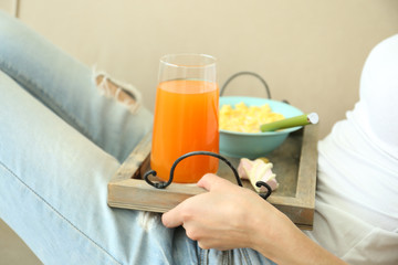 A girl with a tray having lunch on a sofa, close-up