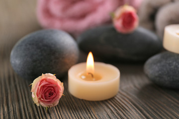 Spa composition of candles, flowers and stones on brown wooden background