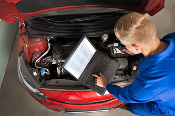 Mechanic Using Laptop To Repair Car
