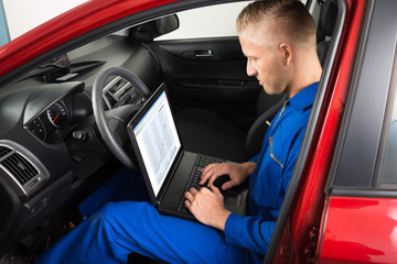Mechanic Sitting In Car And Using Laptop