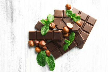 Chocolate pieces with nuts on color wooden background