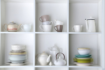 Different clean dishes on wooden shelves