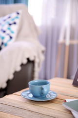 Cup with hot drink on coffee table, on home interior background