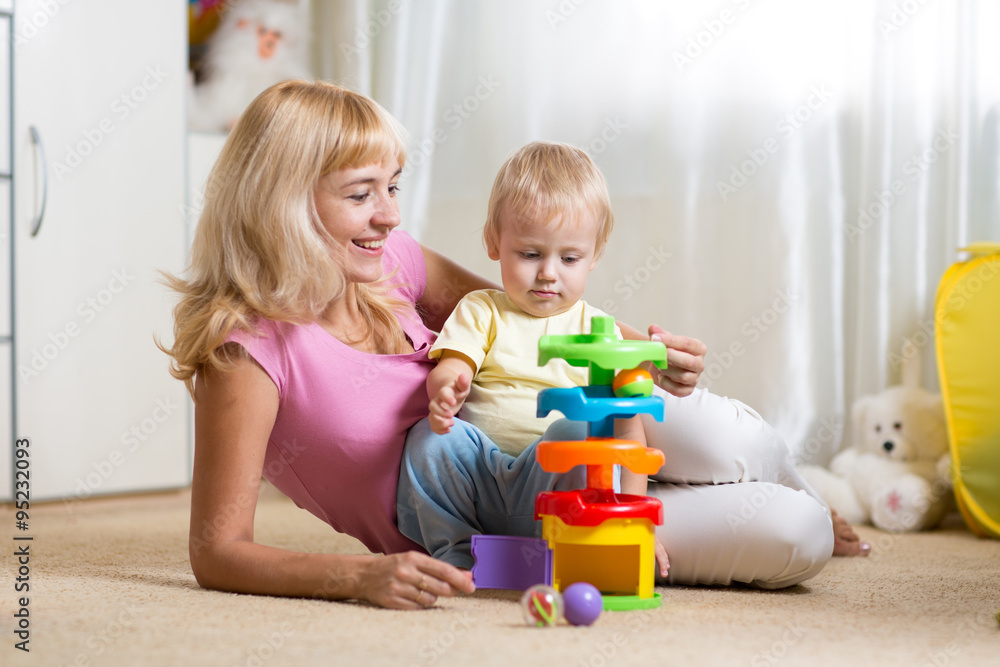 Wall mural mother and her child playing with colorful logical toy