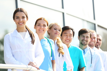 Smiling medics team standing in a row near the clinic