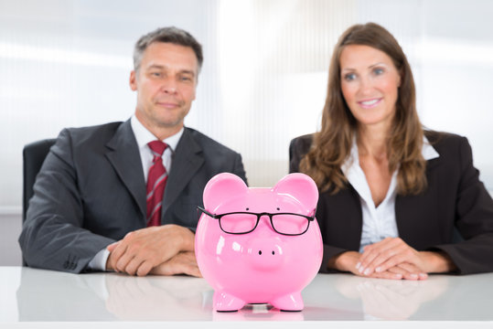 Two Businesspeople Looking At Piggybank
